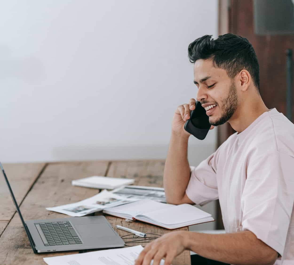 Guide To Improving Cyber Security For Recruitment Firms Man on the phone working on laptop after working with a cyber security for recruitment firms partner